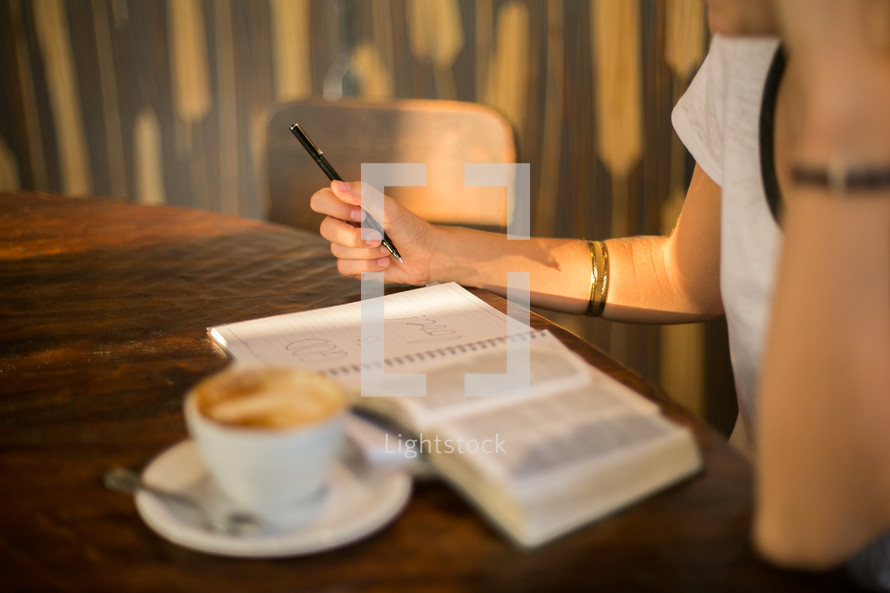 a woman reading a Bible at a Bible with a cappuccino 