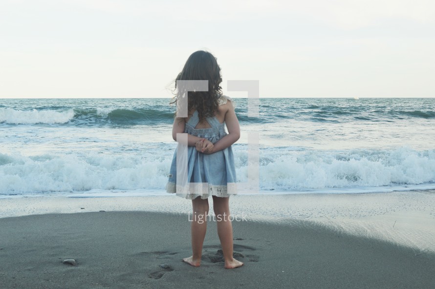 little girl standing on a beach 