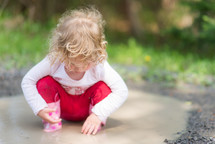 toddler girl playing in a puddle 