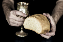 man holding a chalice of wine and a loaf of bread 