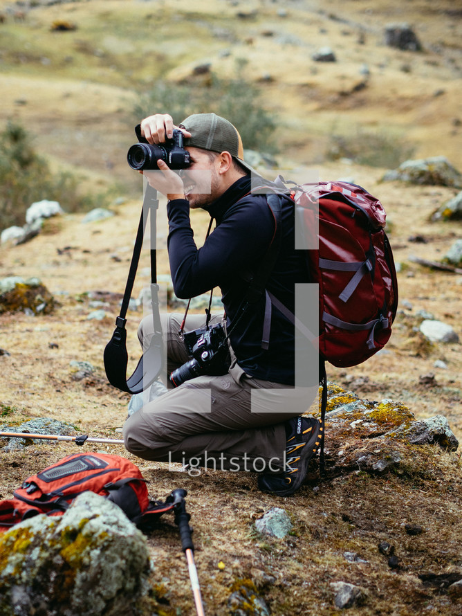 man backpacking taking a camera 