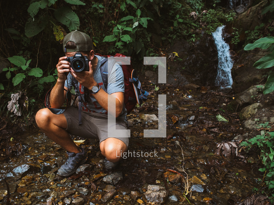man taking a picture with a camera in a forest 