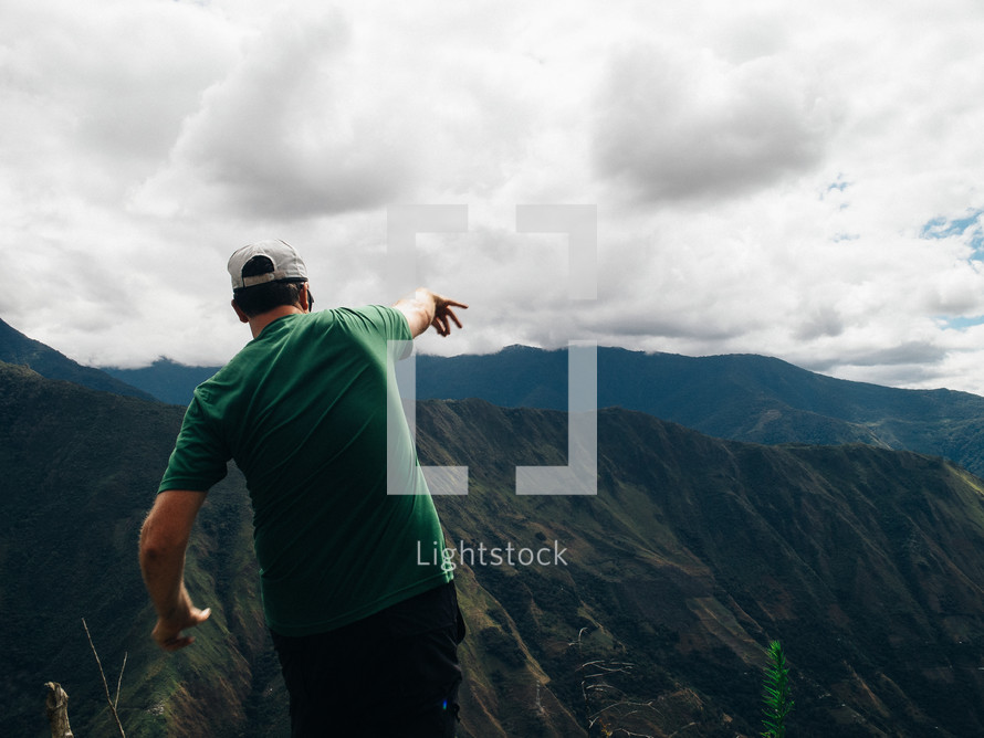 A man throws a rock from a mountaintop.