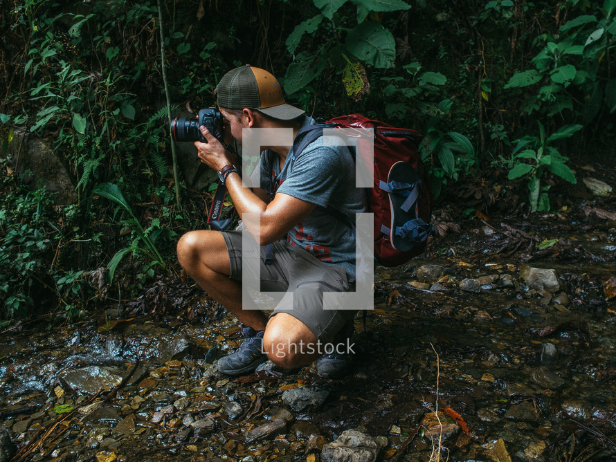 man taking a picture with a camera in a jungle 