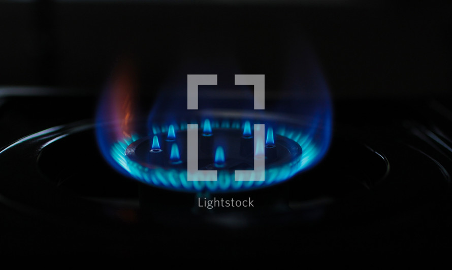 Natural gas blue fire flame on kitchen burner gas stove on dark background. Circular gas-jet. Flame Gas Burner Operation. Shortage and crisis
