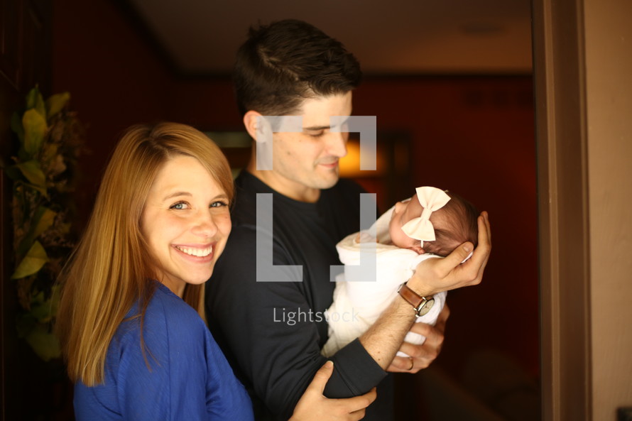 Smiling couple holding their infant daughter.
