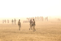 men and women walking through the desert 