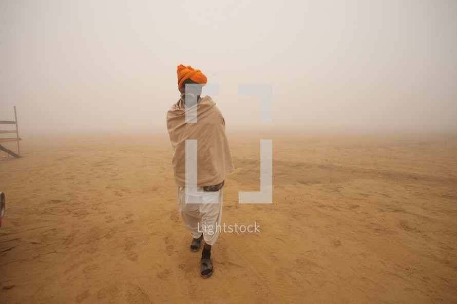 man walking in a desert during a dust storm 