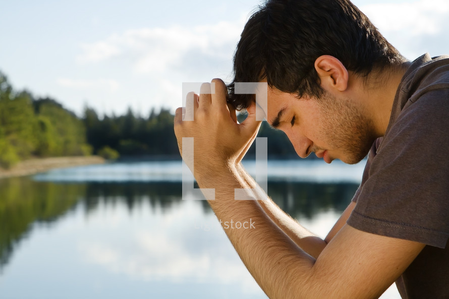 man praying by a lake