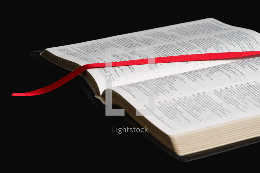 red ribbon bookmark on the pages of a Bible 