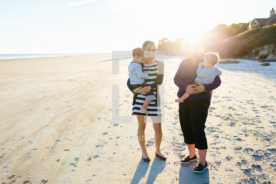 mother and grandmother holding children on a beach 