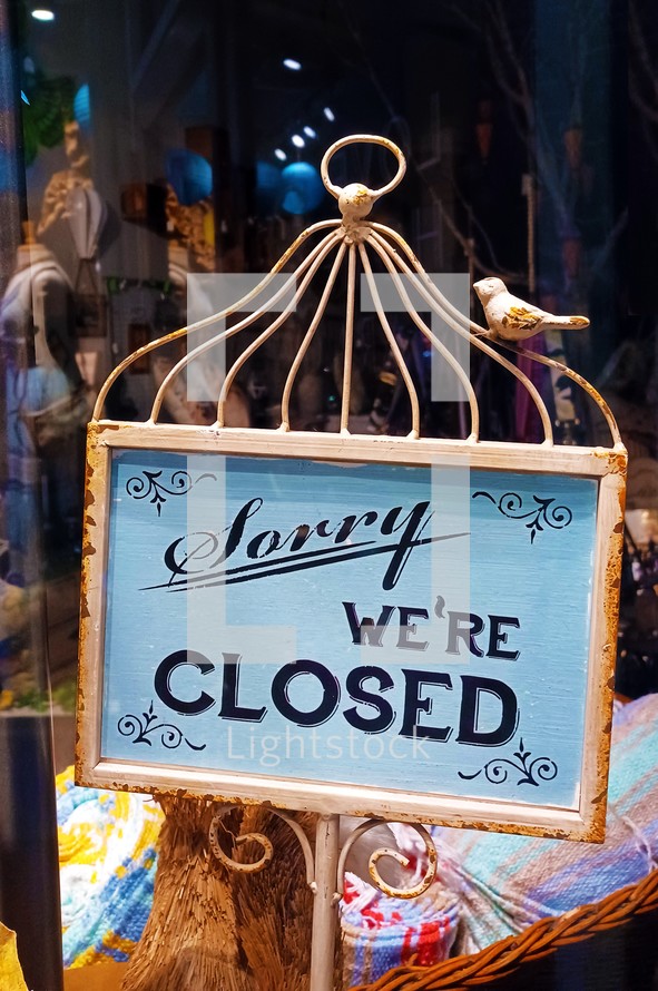 Rusty iron "sorry we're closed" sign with bird