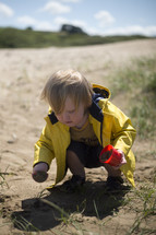 a toddler boy digging in dirt 