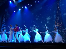 Ballerinas dancing on stage against a blue background for a Christmas performance of The Nutcracker during the Christmas holiday season. 