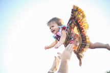 a father tossing his toddler girl in the air 