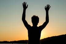 silhouette of a boy with raised arms 