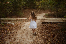 a little girl running on a dirt path 