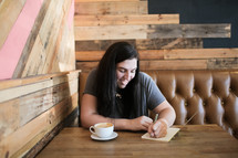 a young woman journaling at a coffee shop 