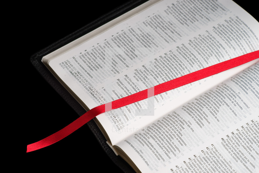 red ribbon bookmark on the pages of an old Bible 