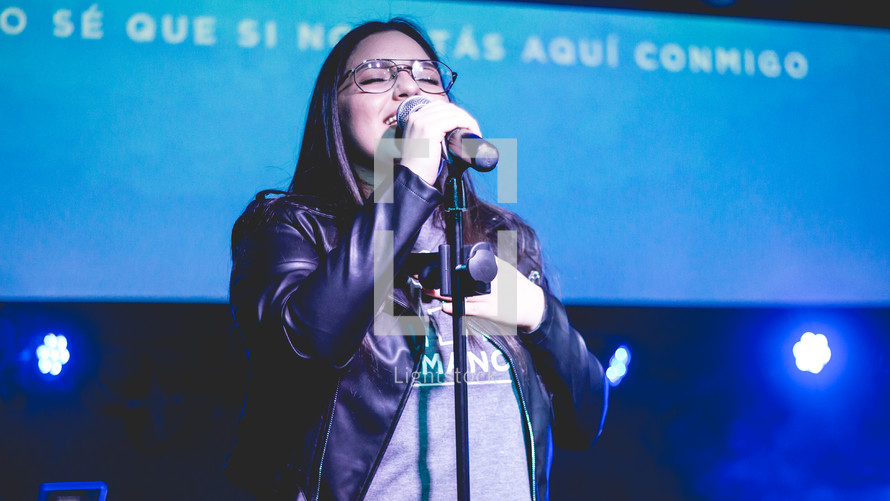 woman holding microphones singing during a worship service 