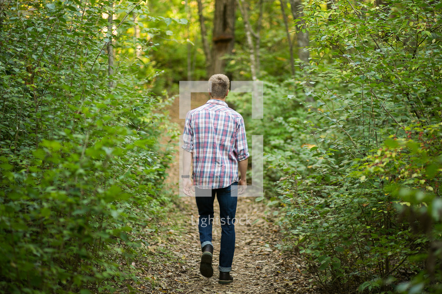 man walking on a path through a forest 