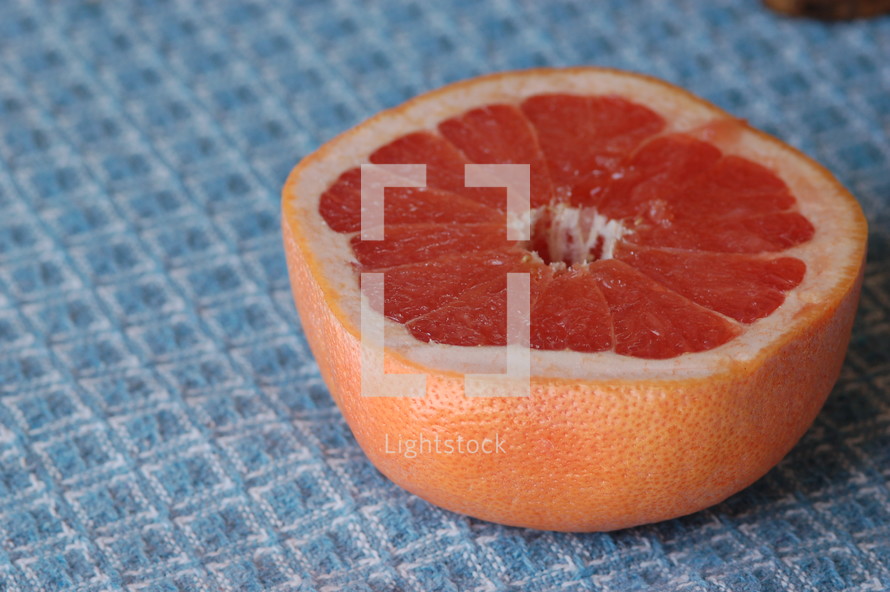 Half of a grapefruit on a blue tablecloth.
