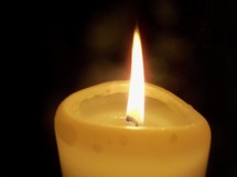 A single lit candle lighting up the darkness and bringing light flickering in the darkness and bringing light, hope and joy to all who seek hope from a dark and stormy world.