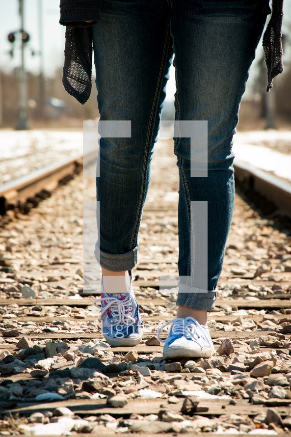 feet of a teen girl standing on a railroad track 