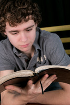Teen reading the Bible at a wooden table.