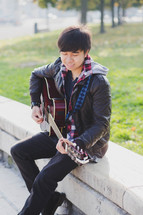 a teen boy playing a guitar 