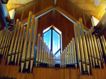 Pipes from a pipe organ in front of a widow