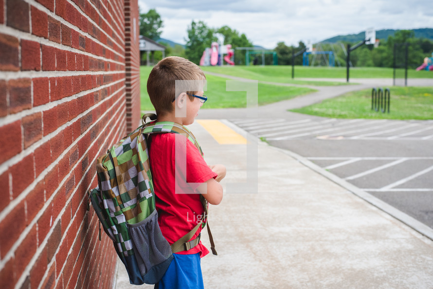 a boy waiting by a school building 
