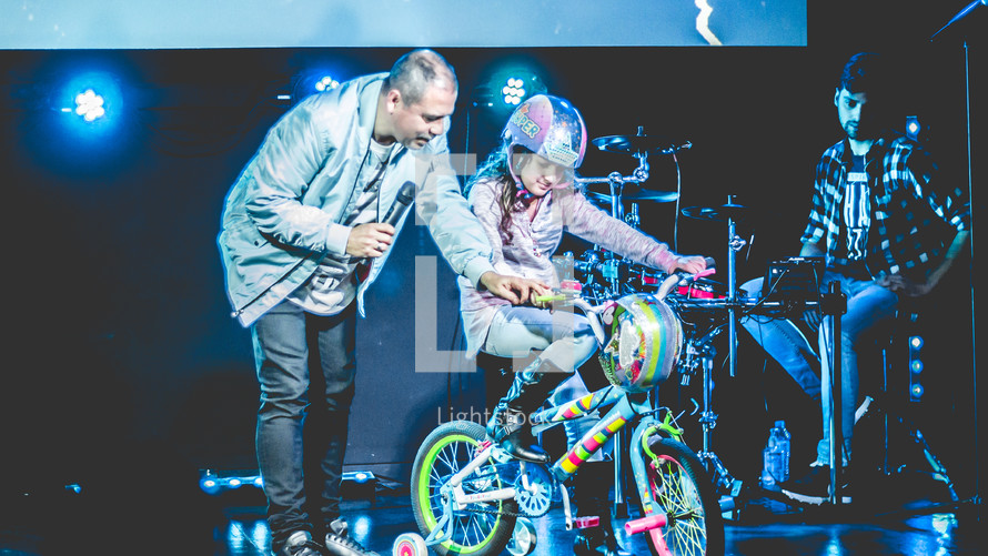 a child giving a bike on stage 