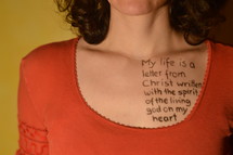 A woman with a scripture written on her chest in ink.