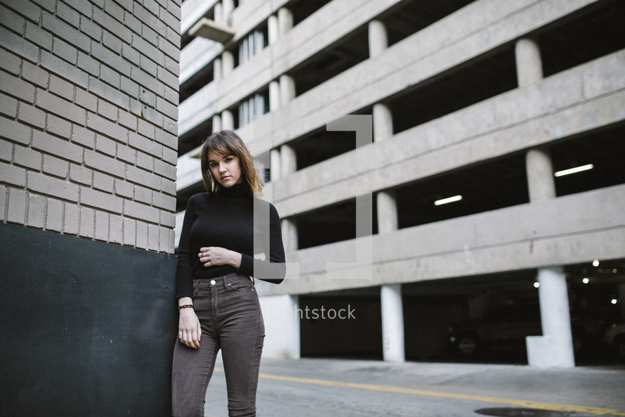 a young woman posing in front of a parking deck 