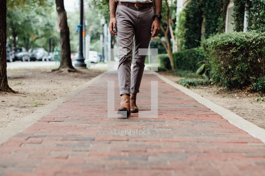 a man walking down a brick sidewalk 