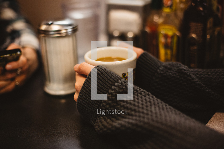 a woman in a sweater holding a mug of coffee 