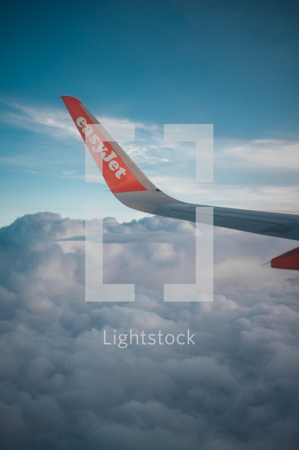 easyJet airplane wing visible above a beautiful cloud sky, aeroplane flight photo of passenger airline journey, travel and vacation photograph