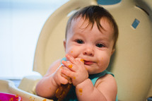 an infant eating baby food in a high chair 