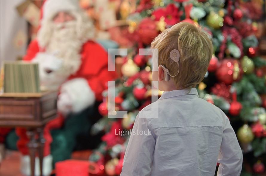 portrait of Boy with Cochlear Implants in front of Santa Claus for Christmas 