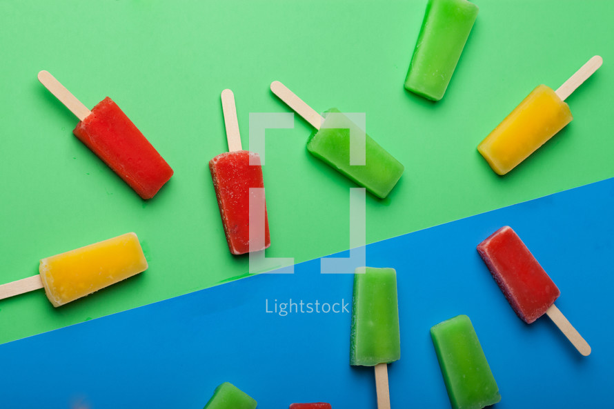 Brightly colored popsicles randomly arranged on a green and blue background.