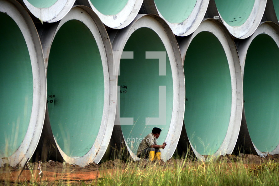 man sitting in large stacked concrete cylinders 