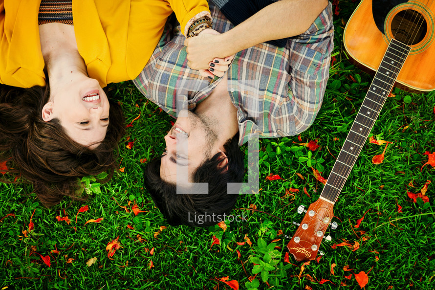 couple lying in the grass and a guitar 