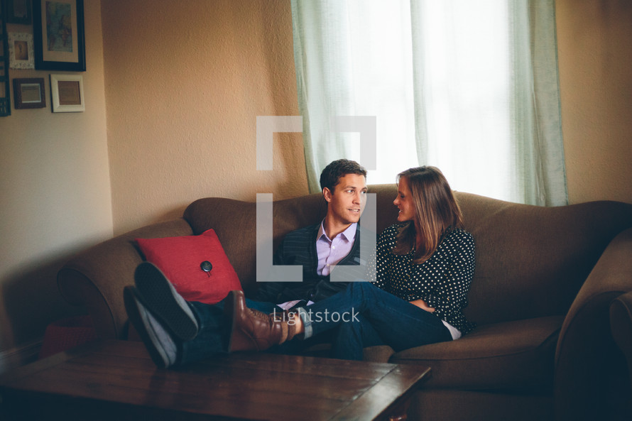 Smiling couple sitting on a sofa with their feet on a coffee table.
