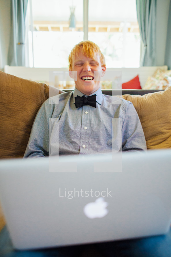 young man with a bow tie with a laptop in his lap 