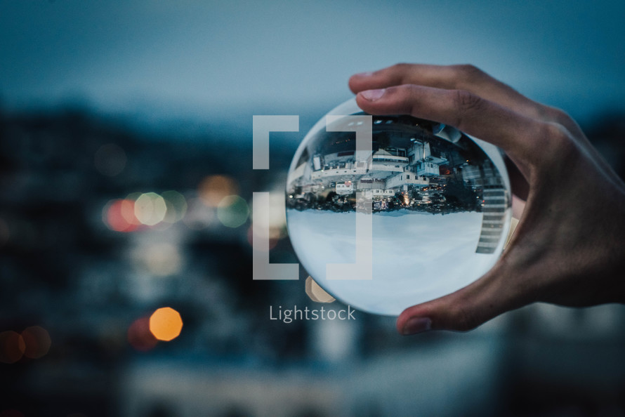 person holding an orb with a view of suburbs 
