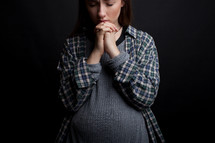 teen girl with a pregnant belly praying 