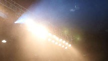 A pan across stage lights with smoke and fog at a concert