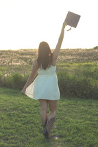 young woman in cowboy boots holding up her graduation cap 