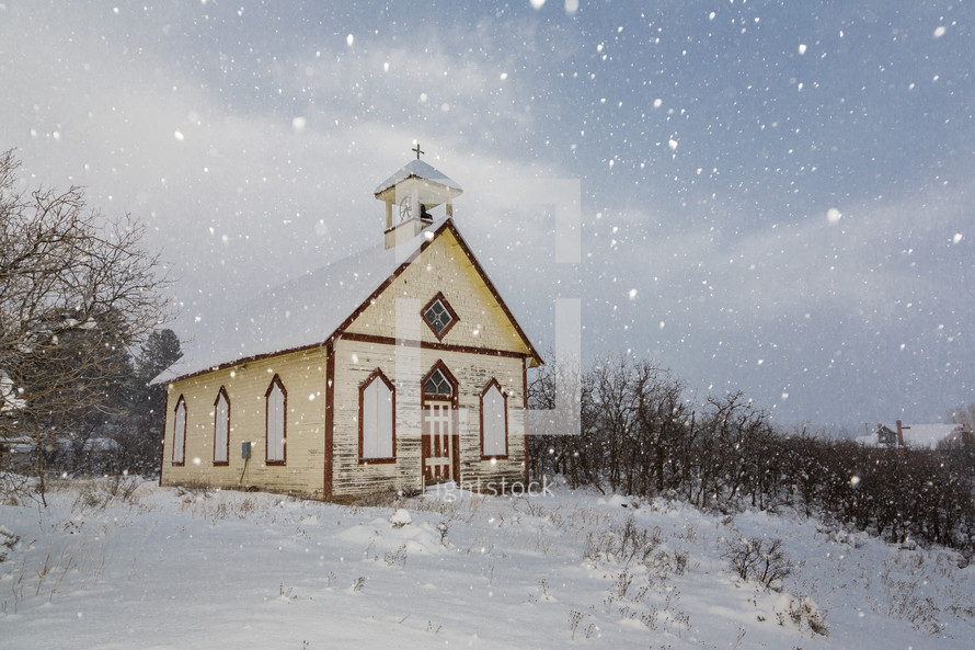 snow falling around a rural church 